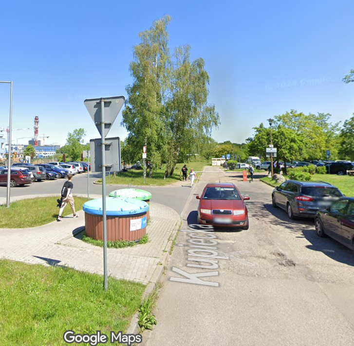 Ulica Kupiecka, parking, drzewa i ludzie.